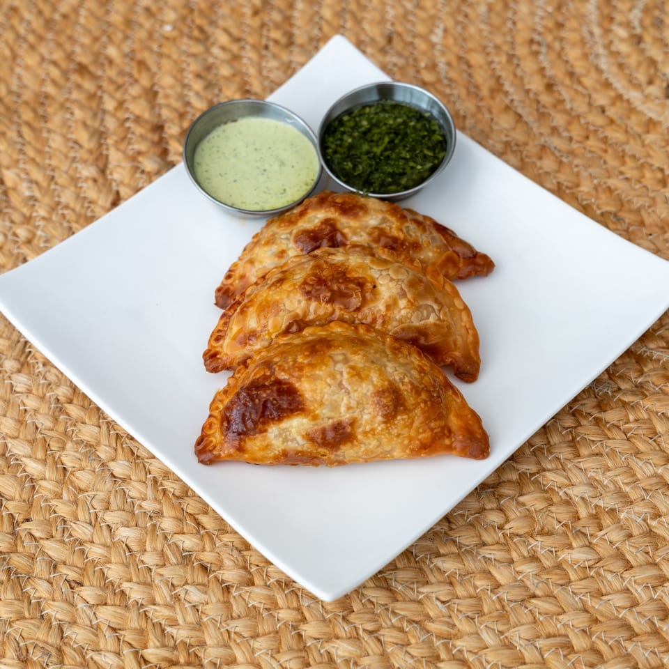 Golden chicken empanadas served with chimichurri and creamy green sauce.