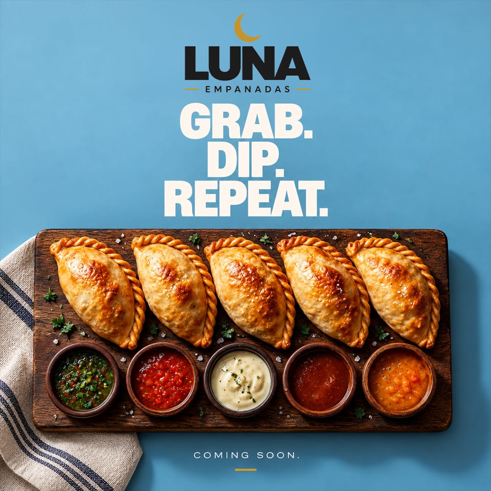 Five golden-brown empanadas with five dipping sauces on a wooden board beneath Luna Empanadas branding.